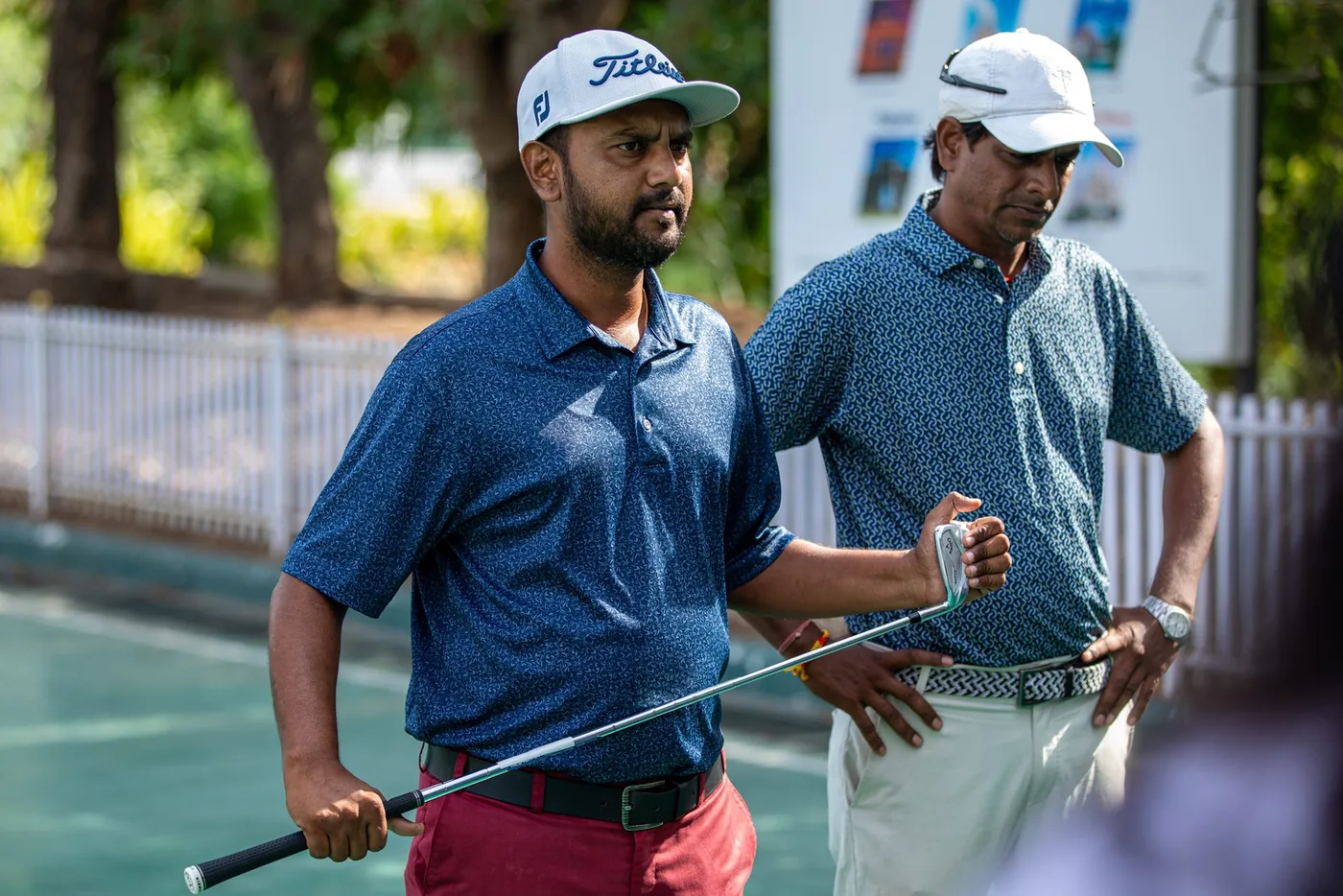 Two participants carrying golf clubs at the GCC Mixer practice range
